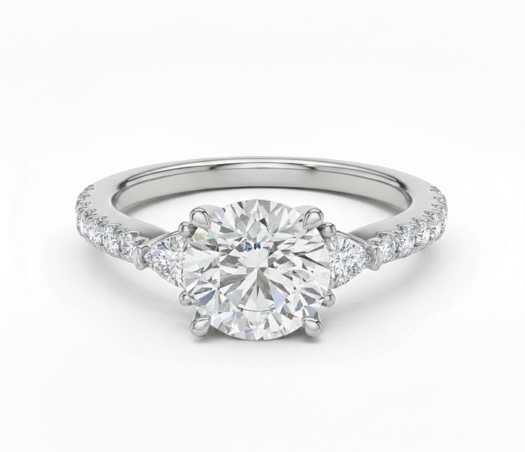 Elegant CZ engagement ring by Riora featuring gold, rose, and silver tones, with sparkling gemstones and a delicate bridal design.